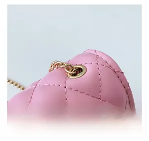 Macro view of pink quilted leather bag with golden metal eyelet and chain strap detail