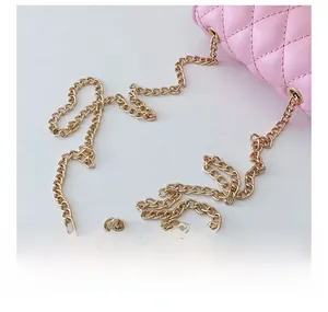 Detail of pink quilted crossbody bag featuring a golden metal chain strap and stitching