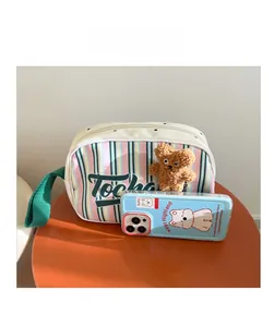 Comparaison de taille du sac enfant rayé avec charm ours à côté d'un smartphone