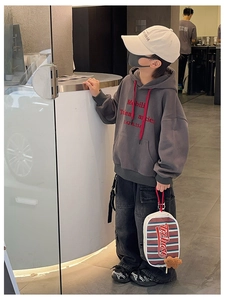 Détail d'une tenue streetwear pour enfant avec sweat à capuche gris et sac à rayures