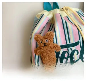 Close-up of colorful striped canvas bag with yellow drawstring and plush bear detail