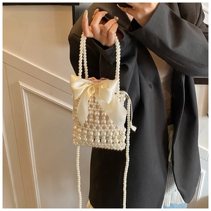 Detail of handmade woven pearl bag featuring a large satin bow and beaded chain strap