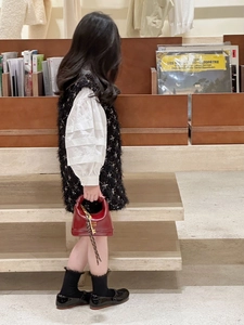 Detail of red glossy mini handbag paired with tweed dress and Mary Jane shoes