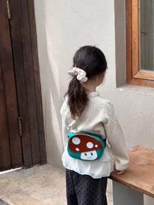 Detailed back view of a cute green mushroom shape crossbody bag on a child model