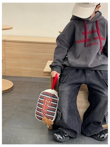 Détail d'un sac à main rayé pour enfant avec pendentif ours et tenue à capuche