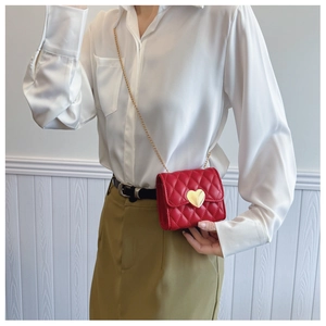 Detail of red quilted mini bag with gold heart clasp and metal chain strap for girls