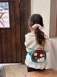 Detail of cute mushroom fanny pack in green canvas with red polka dot hair accessory