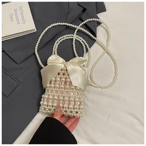 Macro shot of faux pearl woven mini bag with large cream satin bow and pearl strap