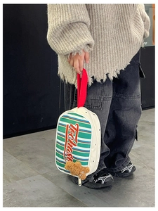 Détail du sac à main rayé pour enfant avec anse rouge et charm ours en peluche