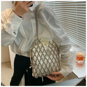Close-up of silver beaded shoulder bag featuring a woven grid and white drawstring pouch