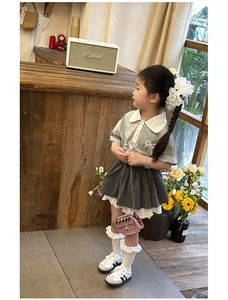 Detail of girls grey polo top and pleated skirt set with cute bow print and pink bag