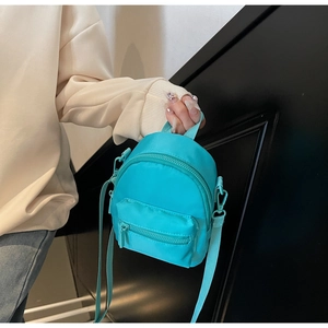 Mini crossbody bag in teal green nylon fabric with adjustable strap and top handle