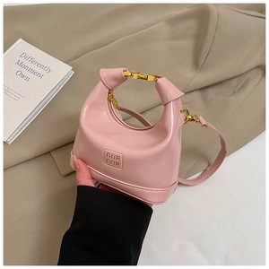 Detail of pink glossy leather handbag with gold metal ring handle and brand logo