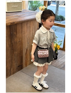 Kids quilted pink mini crossbody bag styled with a grey polo shirt and pleated skirt