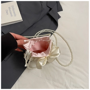 Close-up of the pink satin lining and pearl bead texture on the mini drawstring bag