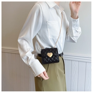 Close-up of small black quilted crossbody bag with gold heart-shaped lock and chain strap