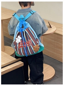 Rear view of striped drawstring backpack with cute plush bear charms on a child