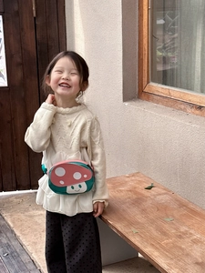 Pink mushroom-shaped waist bag worn by child model in a cozy outdoor garden setting