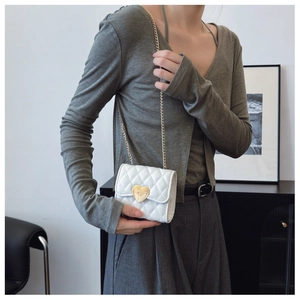 Detailed view of white quilted crossbody bag with golden heart-shaped lock for girls