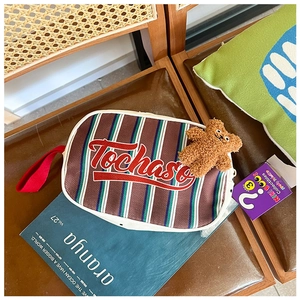 Détail du sac enfant en toile rayée avec poignée rouge et porte-clés ours en peluche