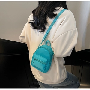 Close-up of lightweight mini crossbody bag in bright blue nylon with zipper details