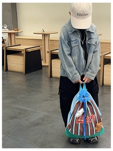 Detail of multi-color striped canvas drawstring backpack with red logo and bear keychain