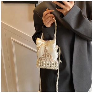Detail of beaded pearl handbag featuring a cream satin bow and woven chain strap