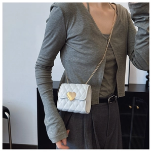 Detail of white quilted crossbody bag for girls with gold heart-shaped metal buckle