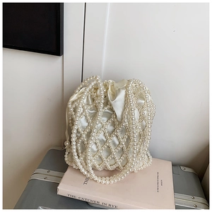Detail of beaded pearl bucket bag featuring a cream satin drawstring pouch and woven handle