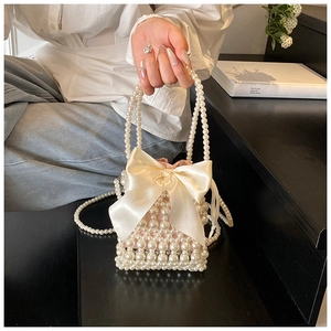 Detail of beaded pearl handbag with large satin bow and detachable shoulder chain strap