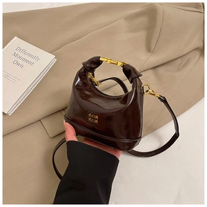 Close-up of a mini brown oil-wax leather handbag with gold metal lock and shoulder strap