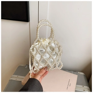 Detail of beaded pearl handbag with cream drawstring lining held in a lifestyle setting