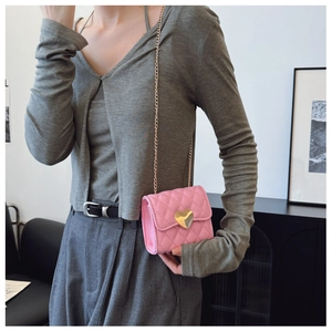 Detailed view of pink quilted mini crossbody bag featuring a gold heart metal twist lock