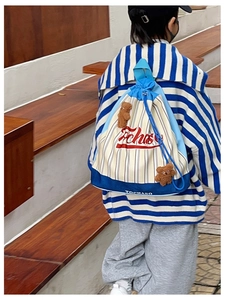 Detail of striped canvas drawstring backpack featuring cute brown plush bear pendants