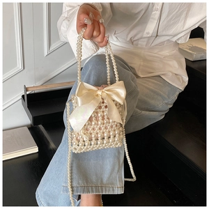 Detailed view of woven pearl handbag with large satin bow held by a model