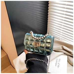 Close-up of metallic green quilted mini bag featuring pearl handle and gold twist lock