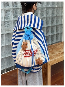 Detail of canvas drawstring kids backpack with blue straps and cute brown teddy bear charms