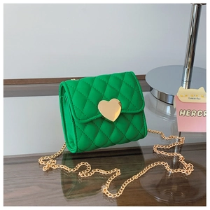 Detail of green quilted mini bag with golden heart-shaped lock and metal chain strap