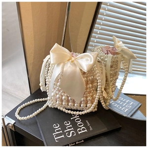 Close-up of handmade pearl bucket bag featuring a large white satin bow and drawstring liner