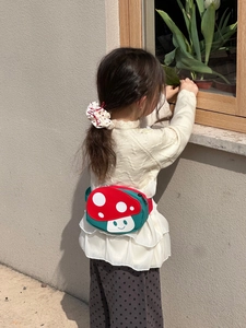 Detail view of a cute mushroom waist bag for kids worn by a girl in a natural home setting