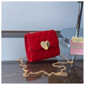 Close-up of red quilted mini bag featuring a gold heart clasp and fine chain strap
