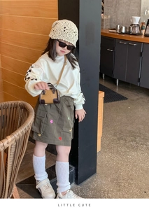 Tenue d'automne pour fille avec sweat blanc, jupe olive et mini sac à bandoulière chic