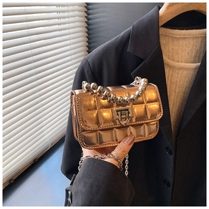 Detail of rose gold metallic quilted mini bag with silver bead handle and metal clasp