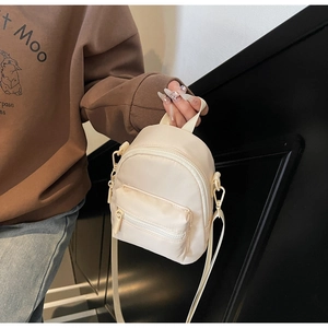 Close-up of mini cream nylon crossbody bag with dual zip pockets and detachable strap