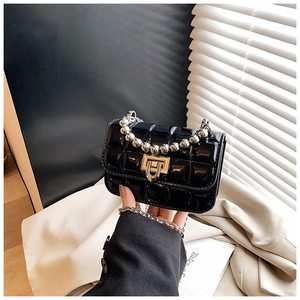 Detail of glossy black patent leather mini bag with silver ball handle and quilted pattern