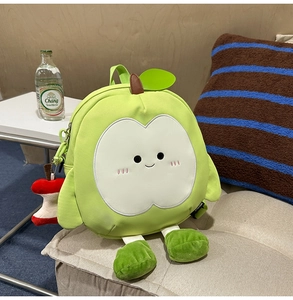 Detail eines apfelförmigen Rucksacks mit Smiley-Gesicht und Plüsch-Apfel-Anhänger