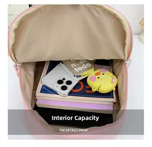 Pink school backpack showing spacious interior with books, smartphone and storage kits