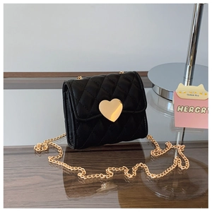 Close-up of black quilted mini bag with golden heart-shaped twist lock and chain strap