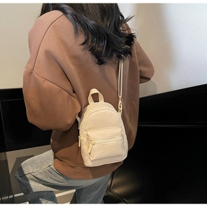Detailed back view of a cream nylon mini crossbody bag shown on a model for size scale