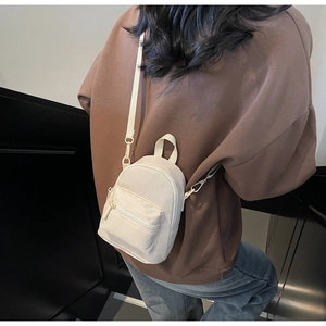 Cream mini crossbody bag on model with adjustable strap and shiny nylon fabric finish